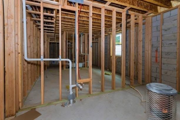 A room in a house under construction with pipes coming out of the walls.
