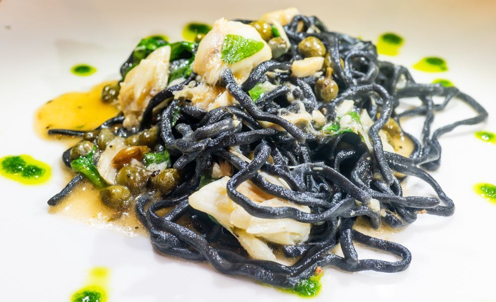 Grilled romaine lettuce salad with shaved Parmesan, dressing, and toasted bread on a white plate.
