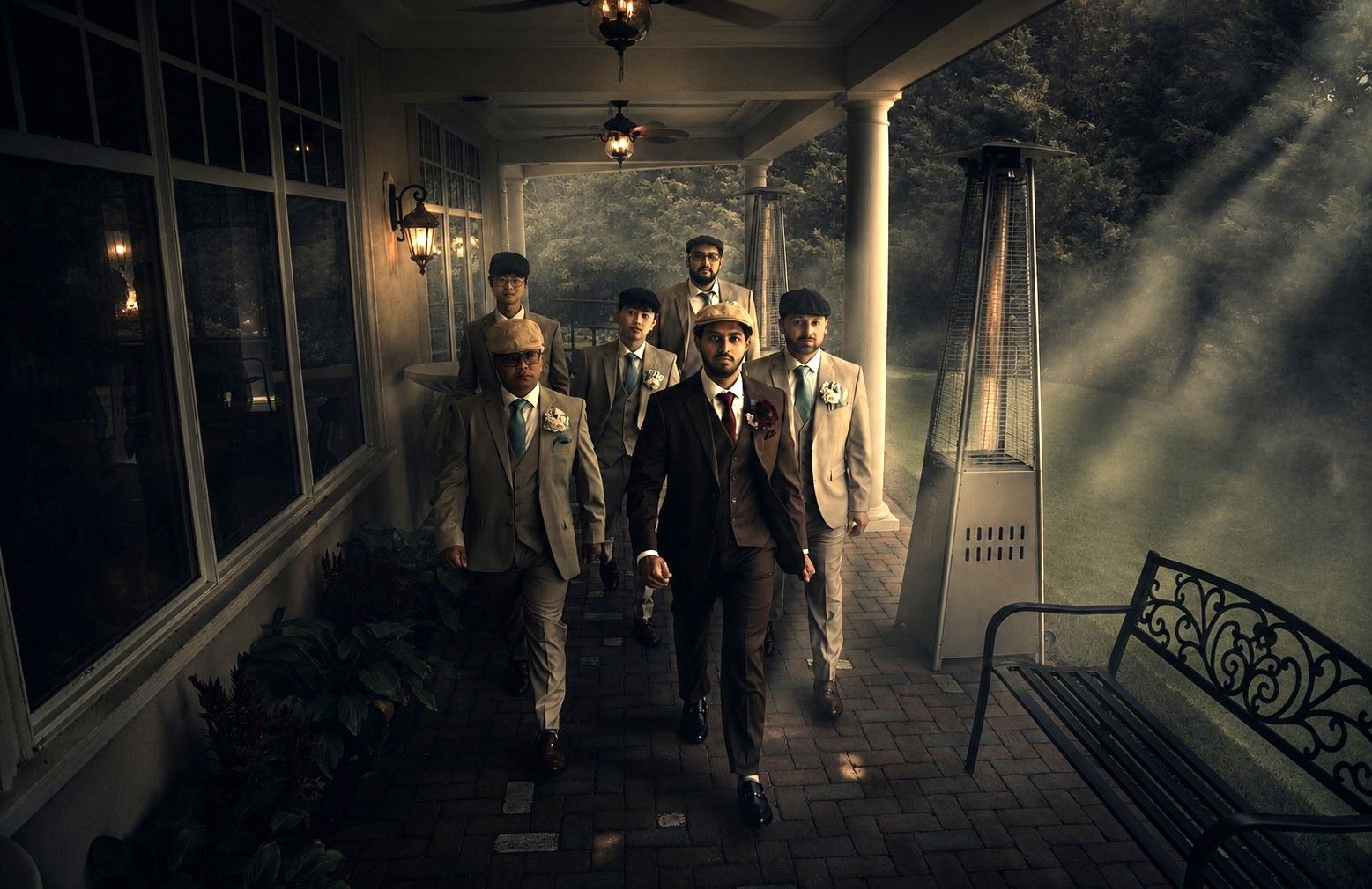 Grooms and groomsmen in suits and newsboy caps walking through fog at The Bradford Estate