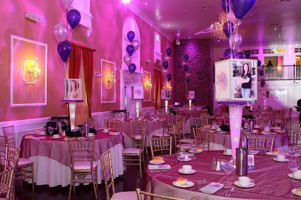 Event space with round tables set for dining, purple and gold decor, balloons.