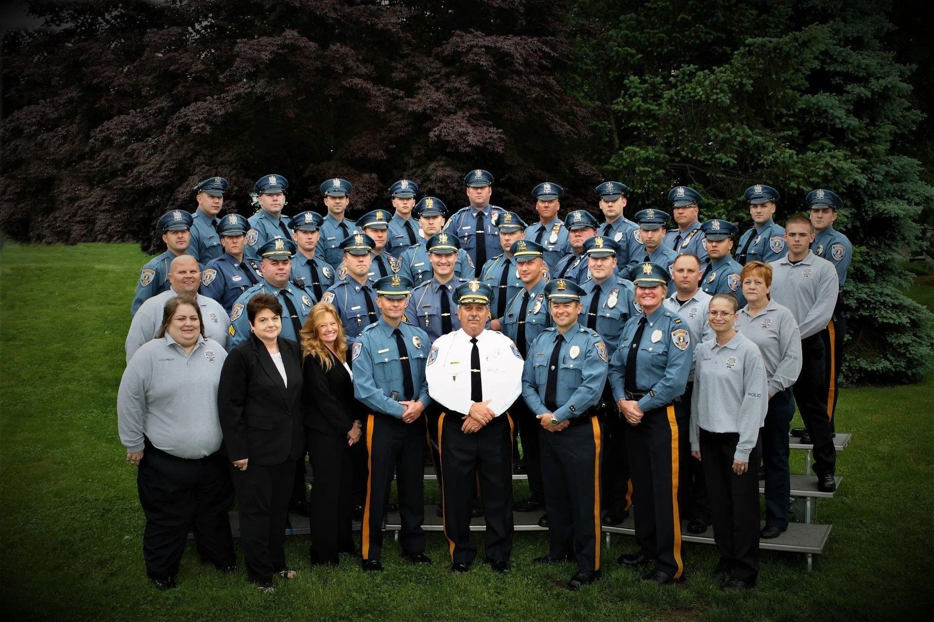 Group of police officers in uniform posing outdoors for a group photo.