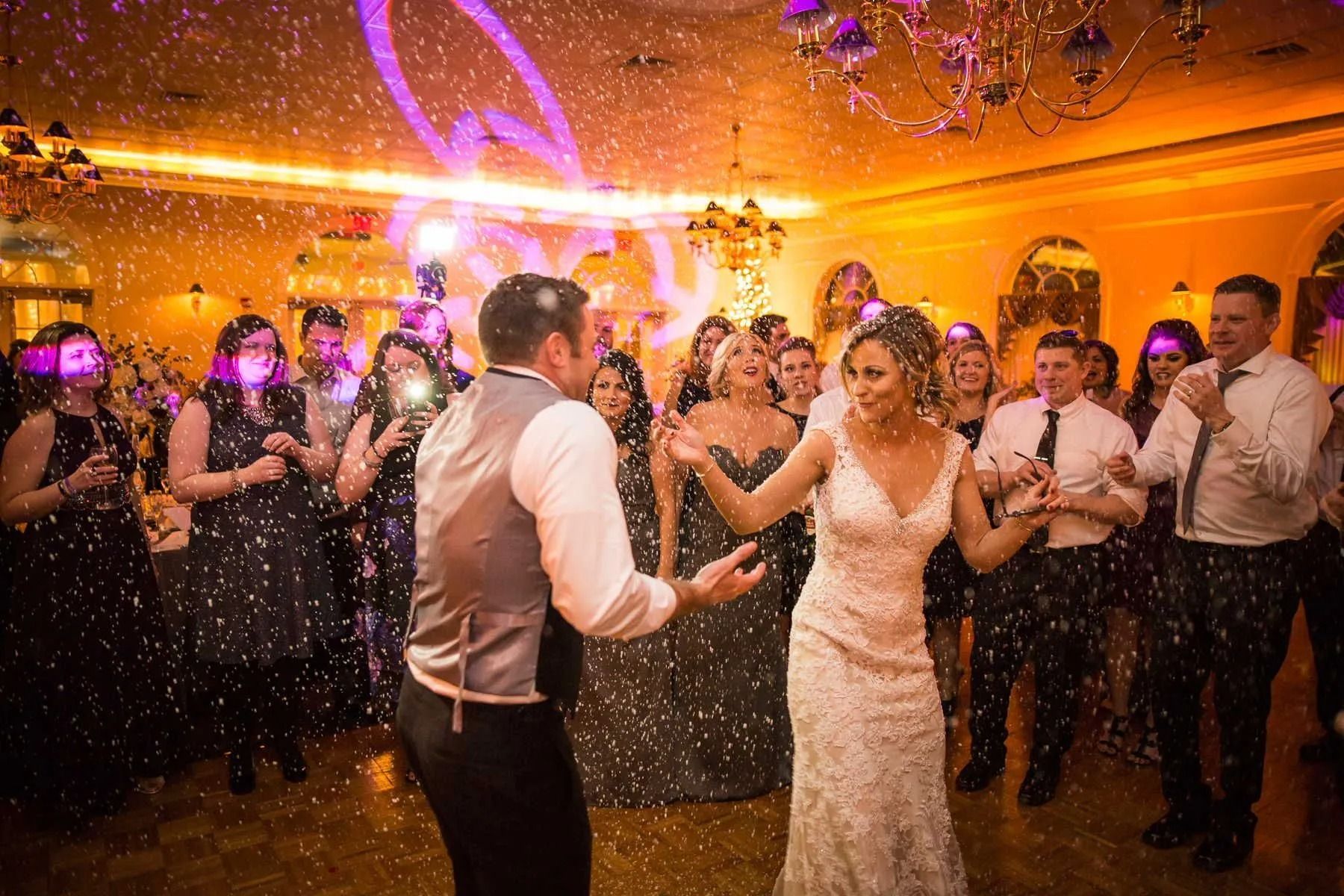Wedding reception: Bride and groom dancing, surrounded by guests, with falling confetti.
