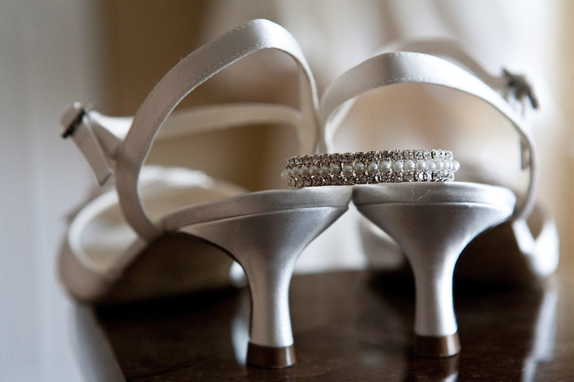 White bridal heels with a bracelet resting on them.
