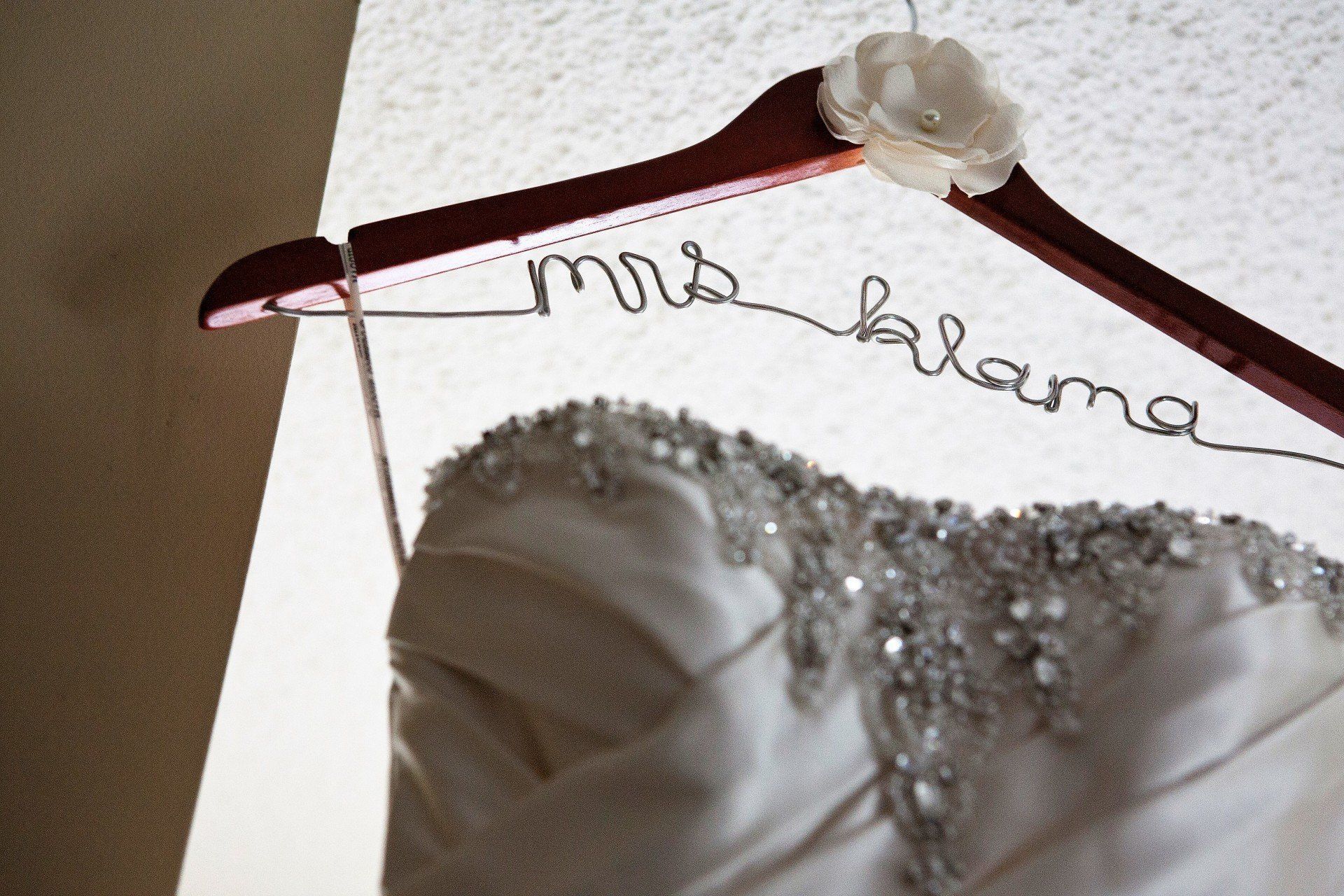 Wedding dress hanging on a wooden hanger with the name 