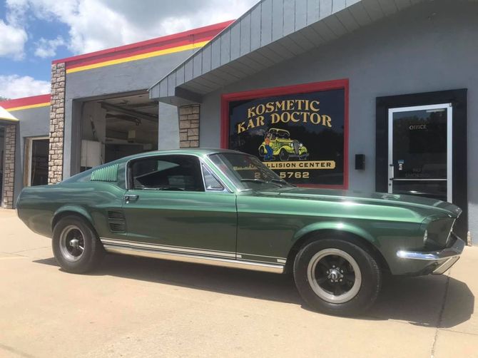 Green classic Mustang parked outside a repair shop,