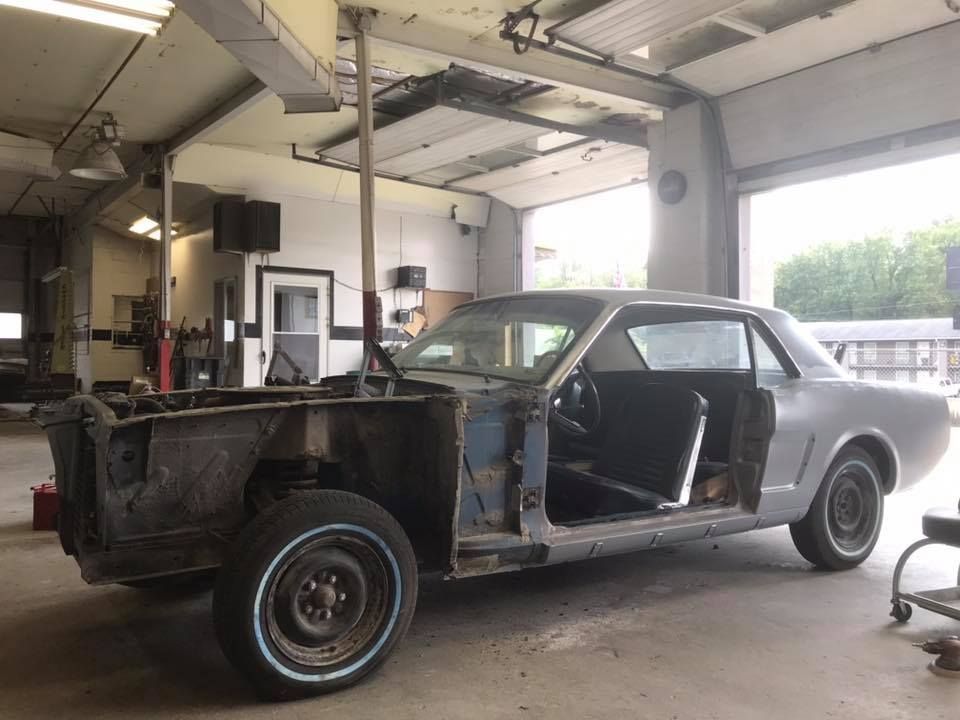 Partially restored, blue classic car in a garage with the front end disassembled.