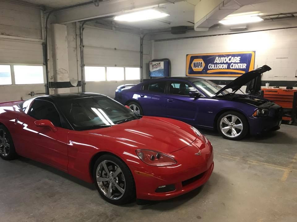 Red Corvette and purple Dodge Charger in a car repair shop.