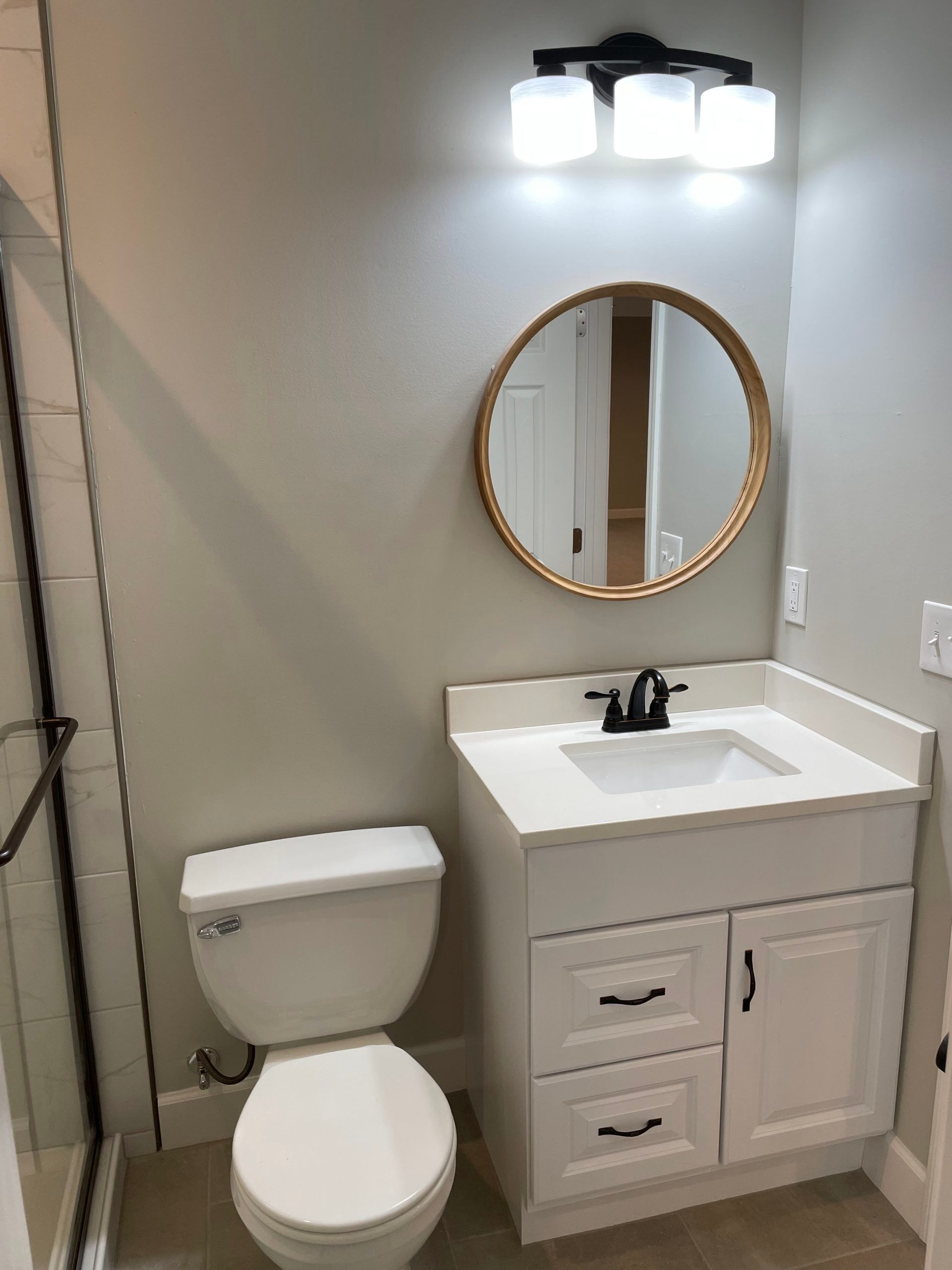 A bathroom with a toilet , sink and mirror.