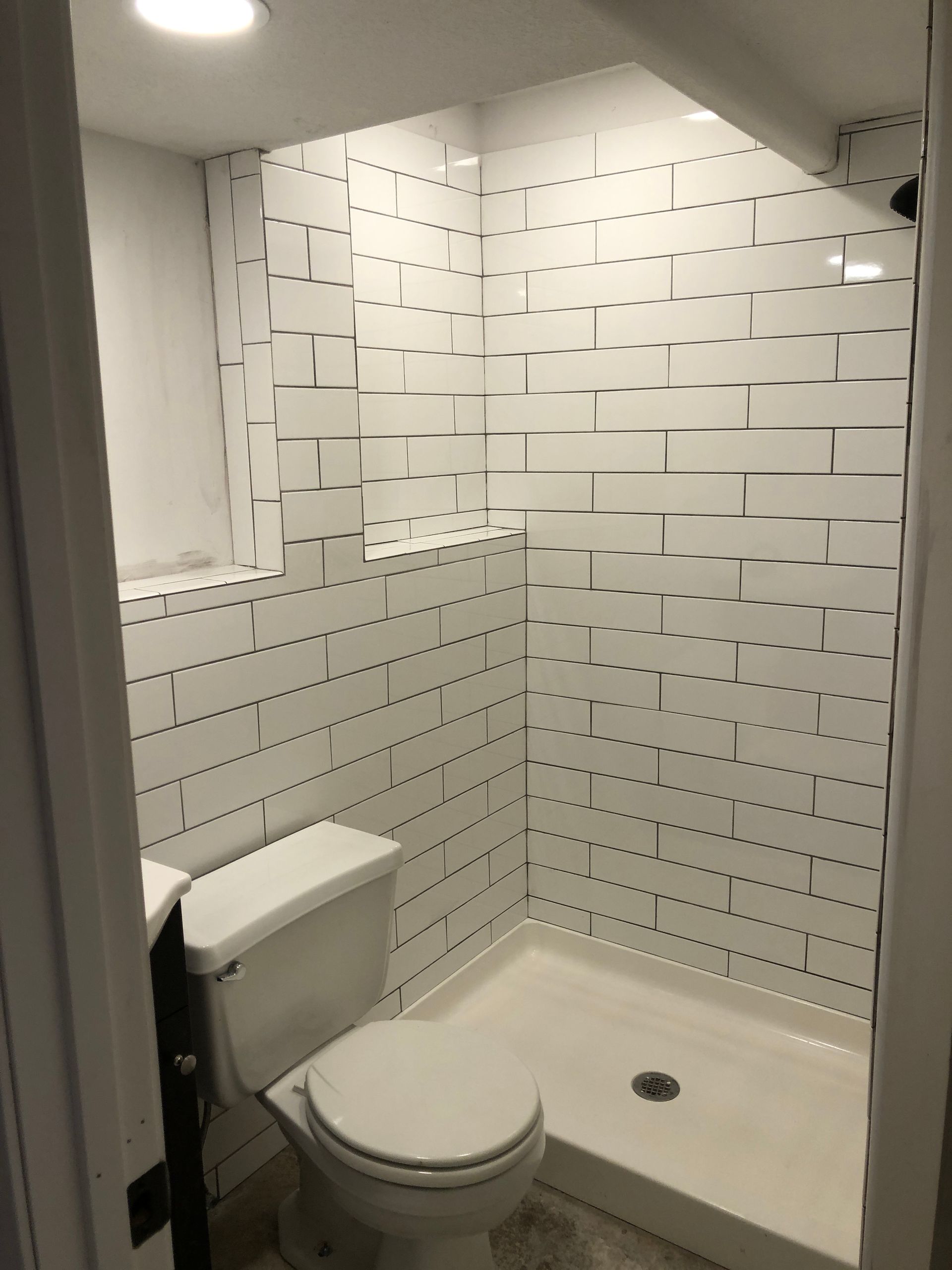 A bathroom with a toilet , sink and shower.