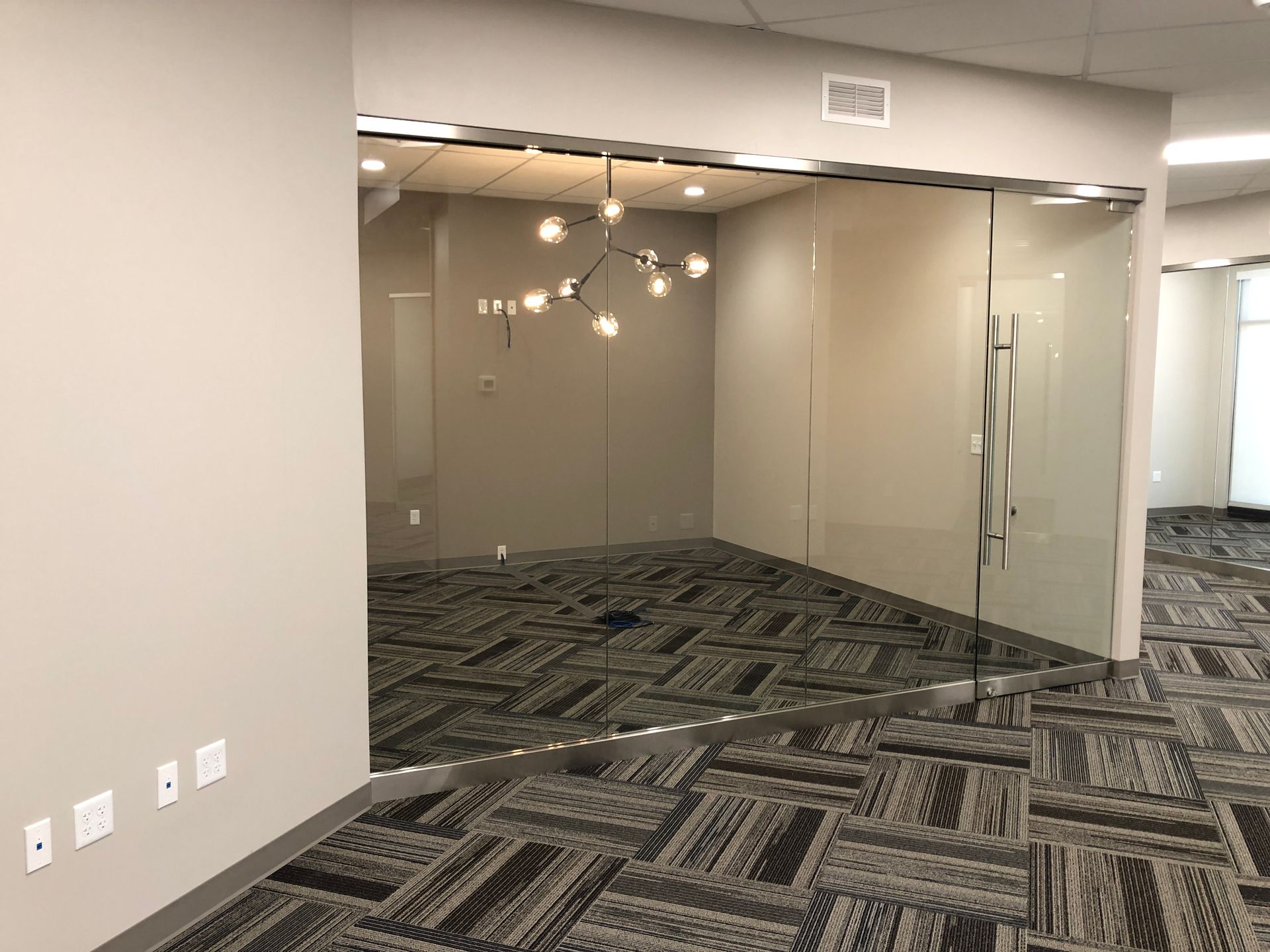 An empty room with a carpeted floor and glass doors.