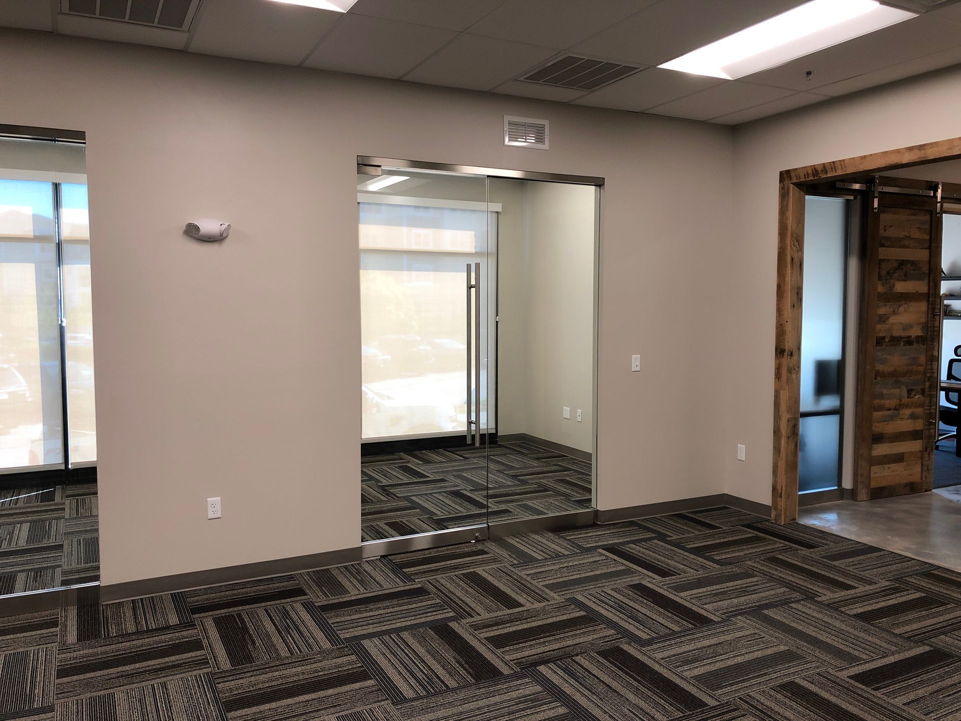 An empty room with a carpeted floor and a glass door.
