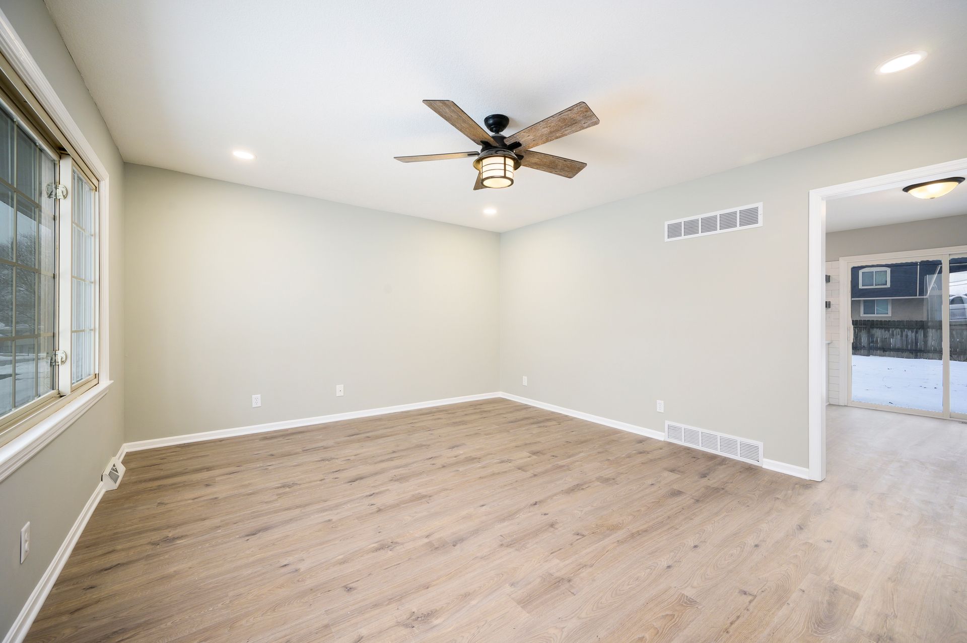 An empty living room with hardwood floors and a ceiling fan.