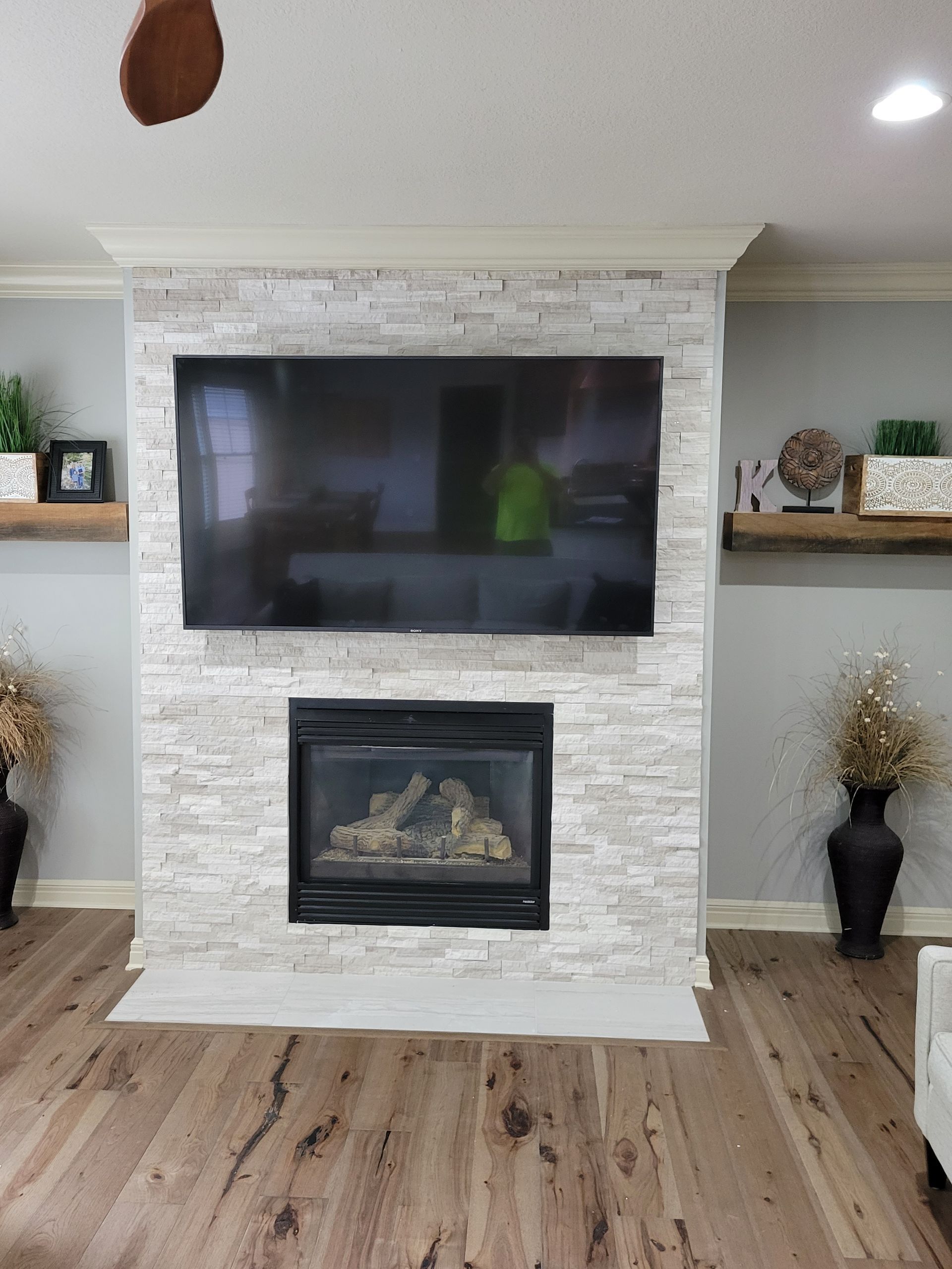 A living room with a fireplace and a flat screen tv on the wall.