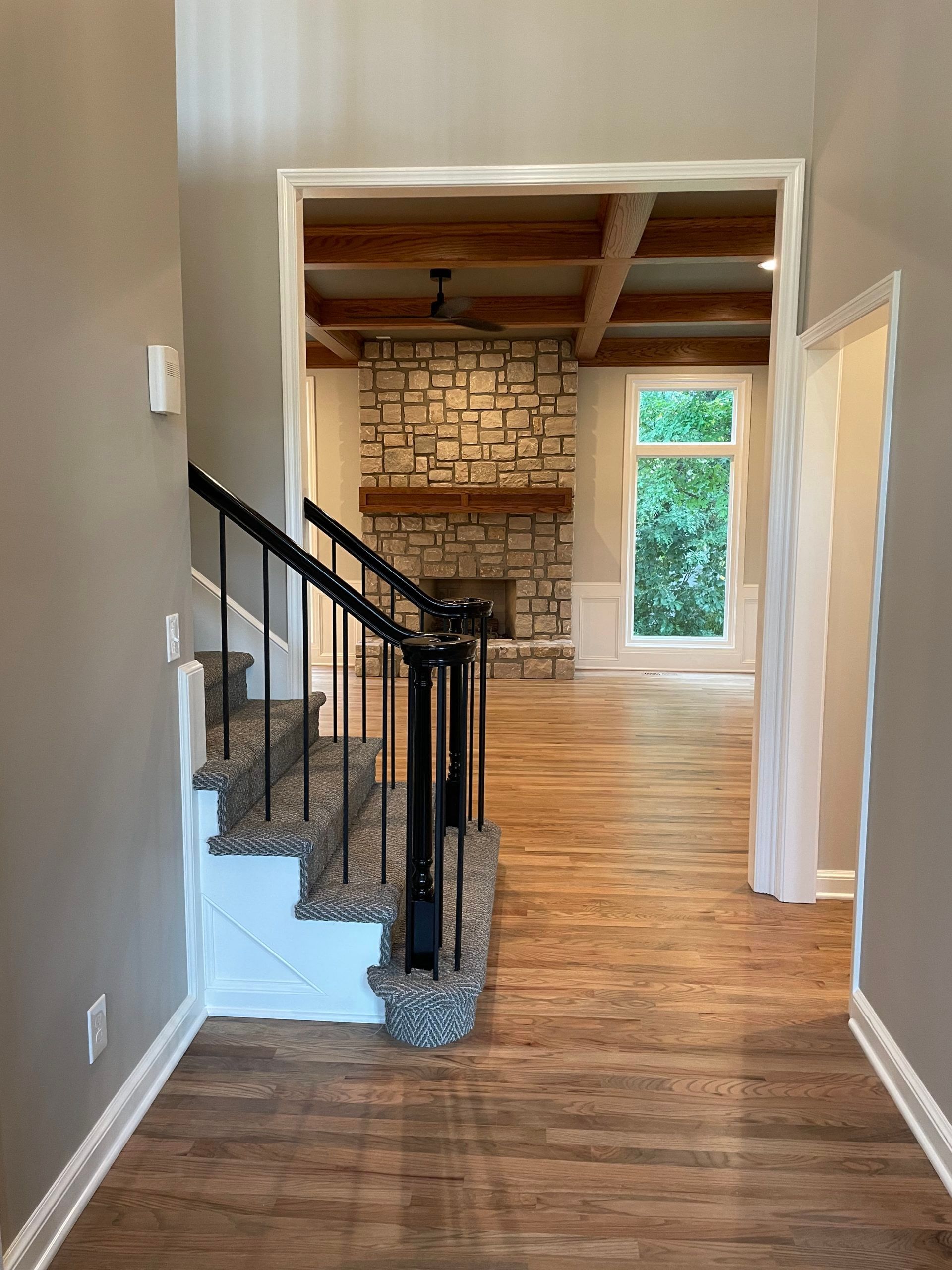 A hallway with stairs and a fireplace in the background.