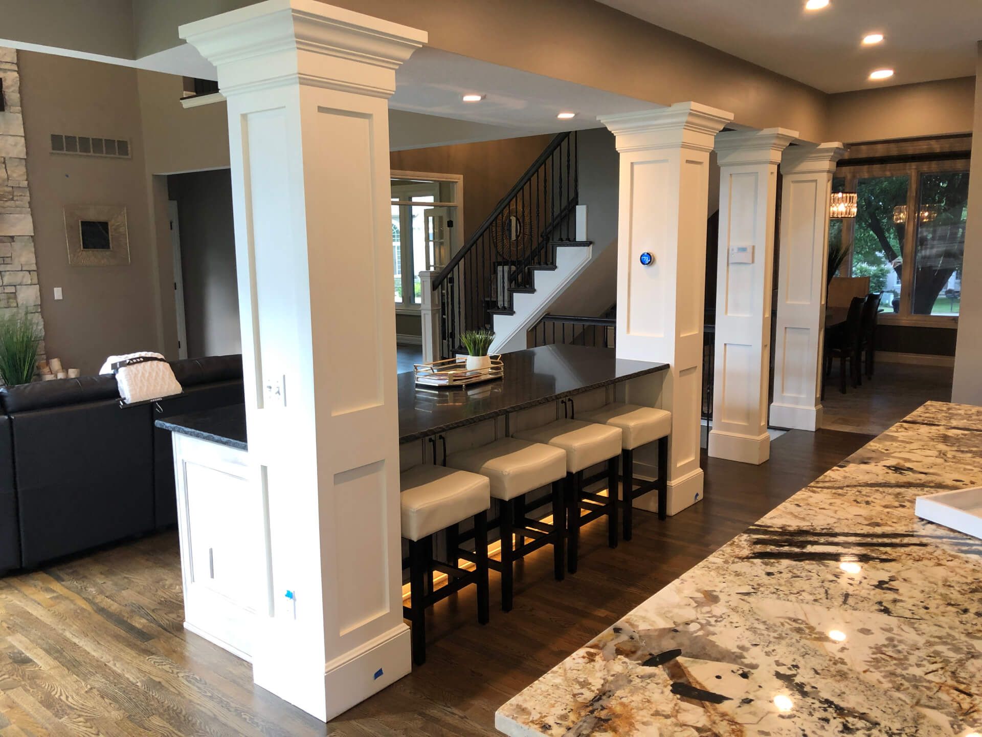 A kitchen with granite counter tops and a staircase in the background.