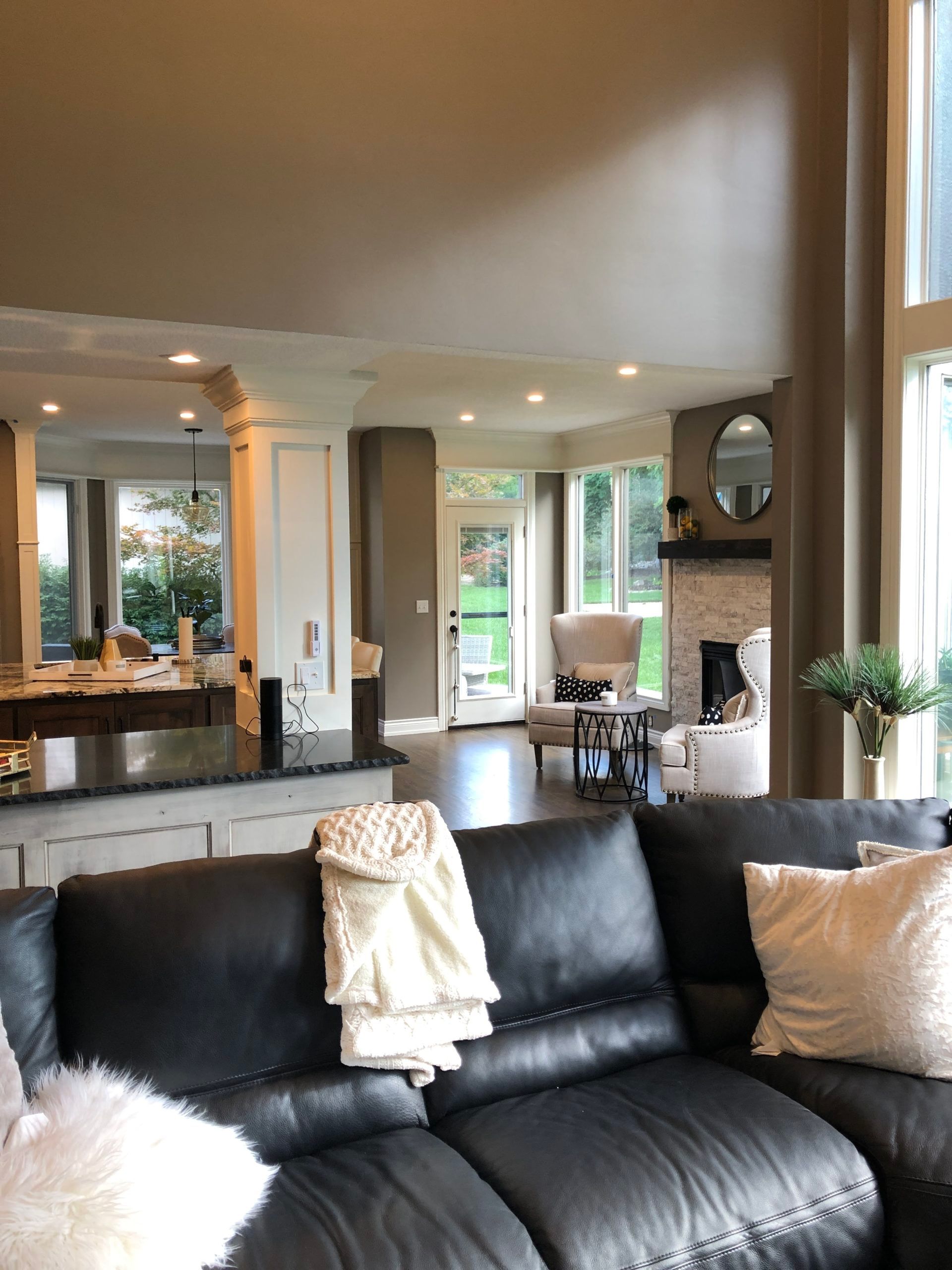A living room with a black leather couch and white pillows