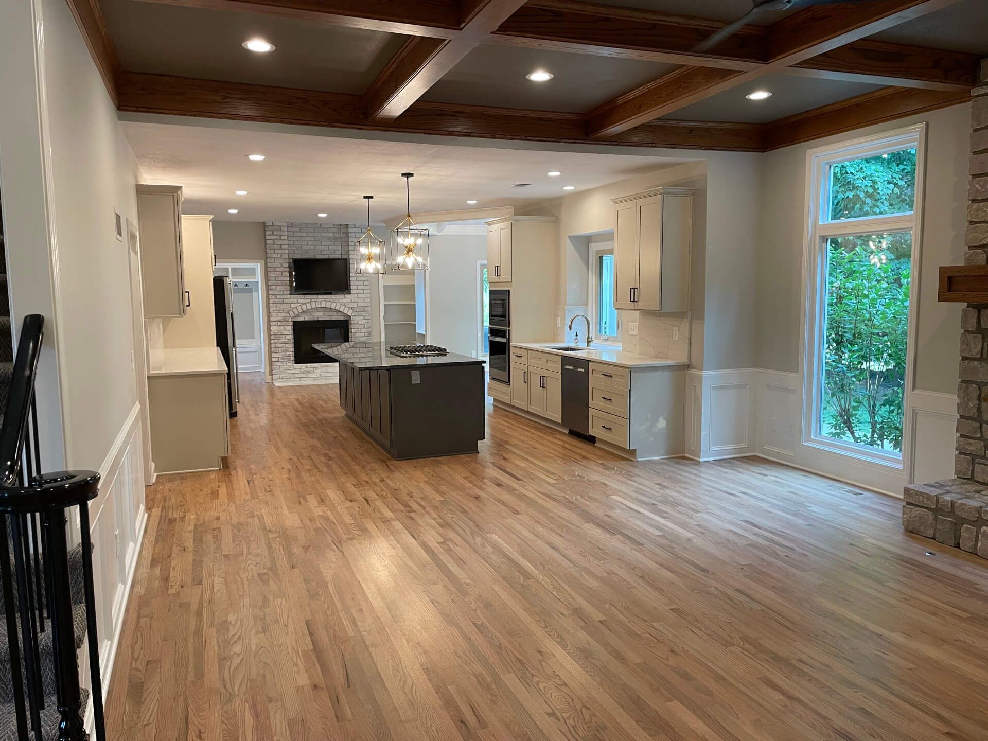 A large empty room with hardwood floors and a kitchen.