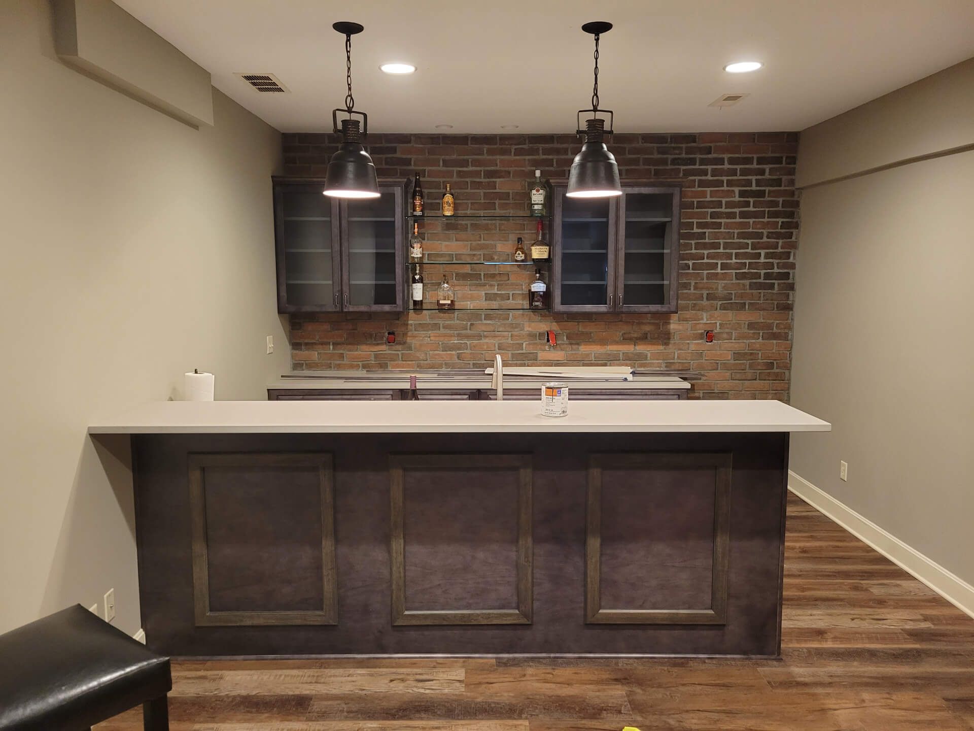 There is a bar in the middle of the room with a brick wall.