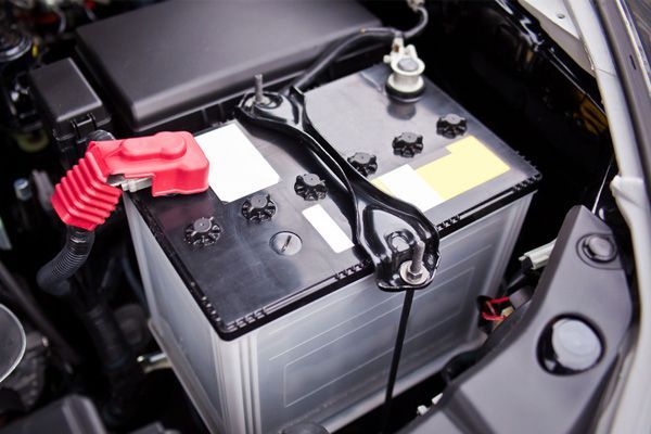 A car battery is sitting under the hood of a car.