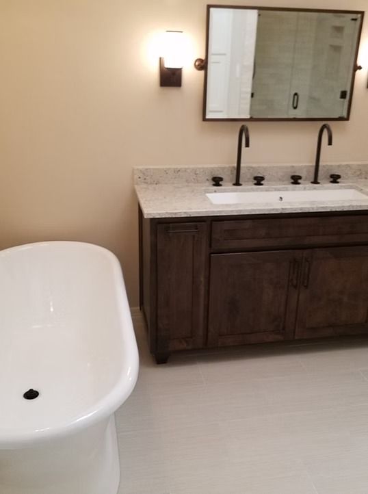 Bathroom with a white freestanding tub and a dark wood vanity with a marble countertop.