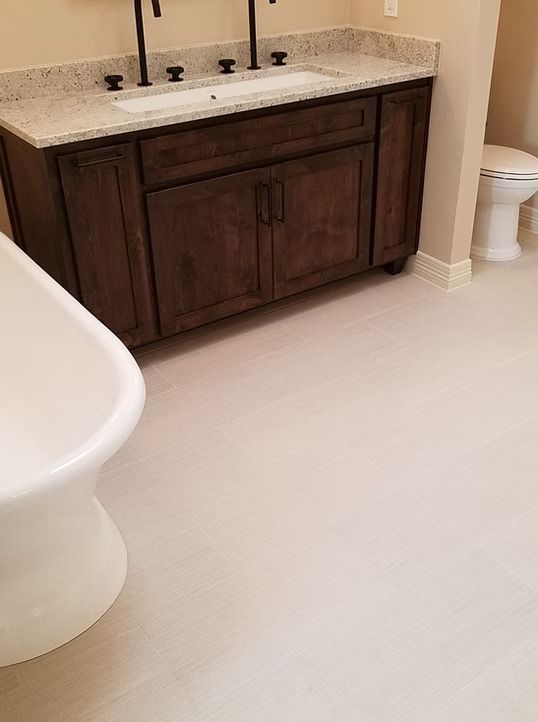 Bathroom with dark wood vanity, light countertop, white sink, toilet, and white floor.