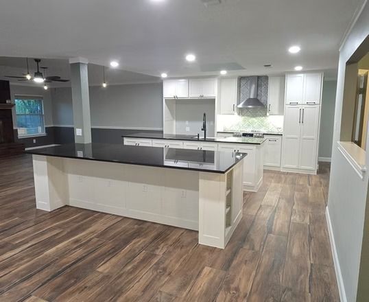Modern kitchen with white cabinets, black countertops, and wood-look flooring.