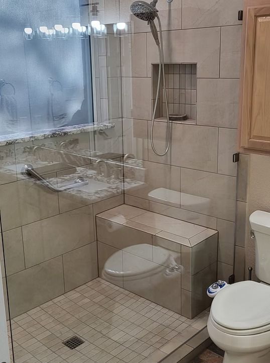 Bathroom with a tiled shower, toilet, and glass door.