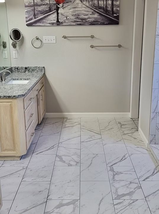 Bathroom with marble-look floor tile, vanity with granite countertop, neutral walls, and two towel bars.