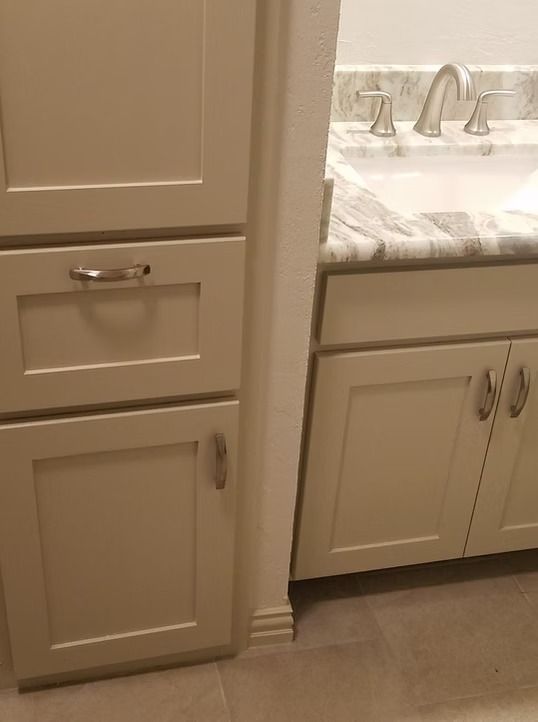 Beige bathroom cabinets with silver hardware and a marble countertop.