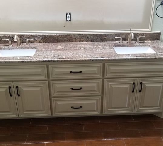 Cream vanity with granite countertop, two sinks, and black hardware.
