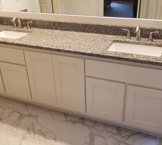 White bathroom vanity with two sinks, granite countertop, and marble tile flooring.