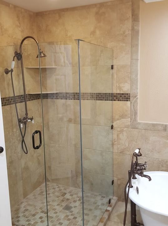 Shower stall with glass doors, brown tile walls, and a vintage-style faucet.