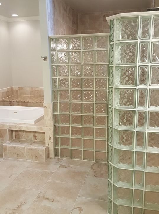 Bathroom with glass block shower walls and tile floors. A built-in tub is visible.