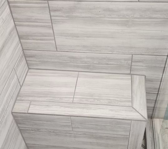 Gray tiled shower interior with a built-in bench.