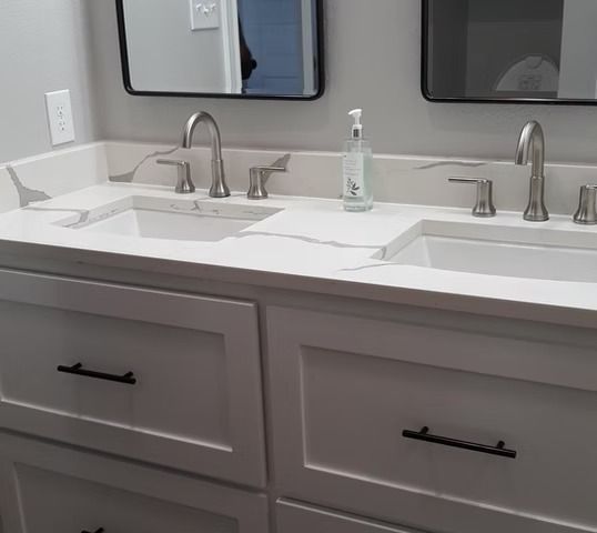 White bathroom vanity with two sinks, silver faucets, and black drawer pulls.
