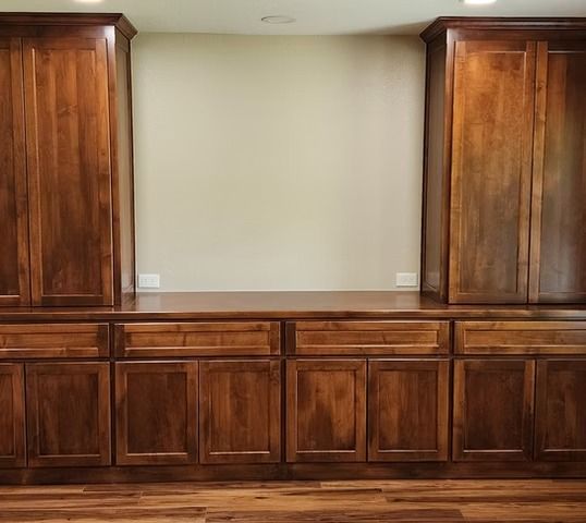 Wooden built-in cabinets with drawers and doors, brown color, against a neutral-colored wall.