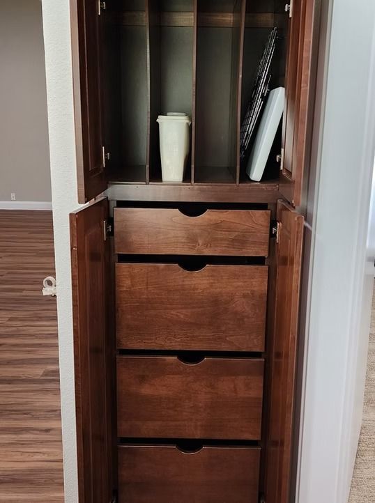 Dark wooden cabinet with drawers and shelves; open, with items inside.