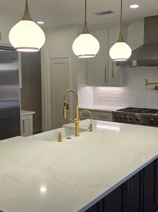 Kitchen with white countertops, gold fixtures, and globe pendant lights.
