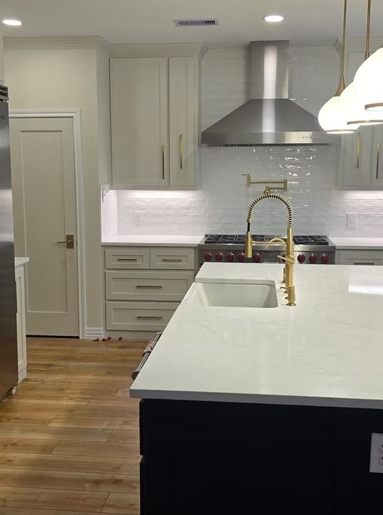 Modern kitchen with light cabinets, white countertops, stainless steel appliances, and a dark island.
