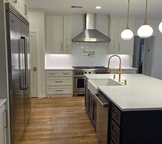 Modern kitchen with white and navy cabinets, stainless steel appliances, and wood floors.
