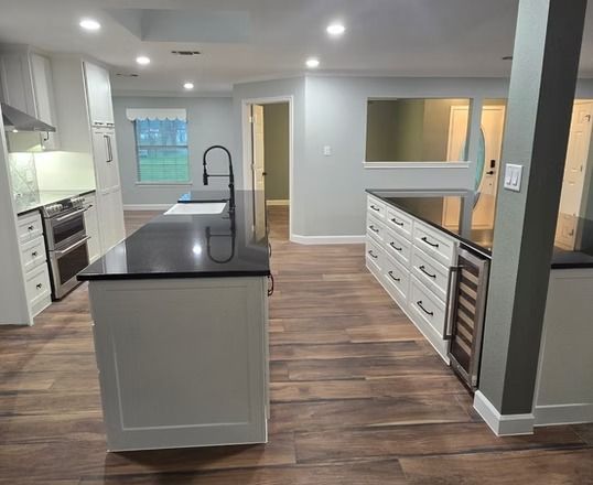 Newly renovated kitchen with white cabinets, black countertops, and wood-look flooring.