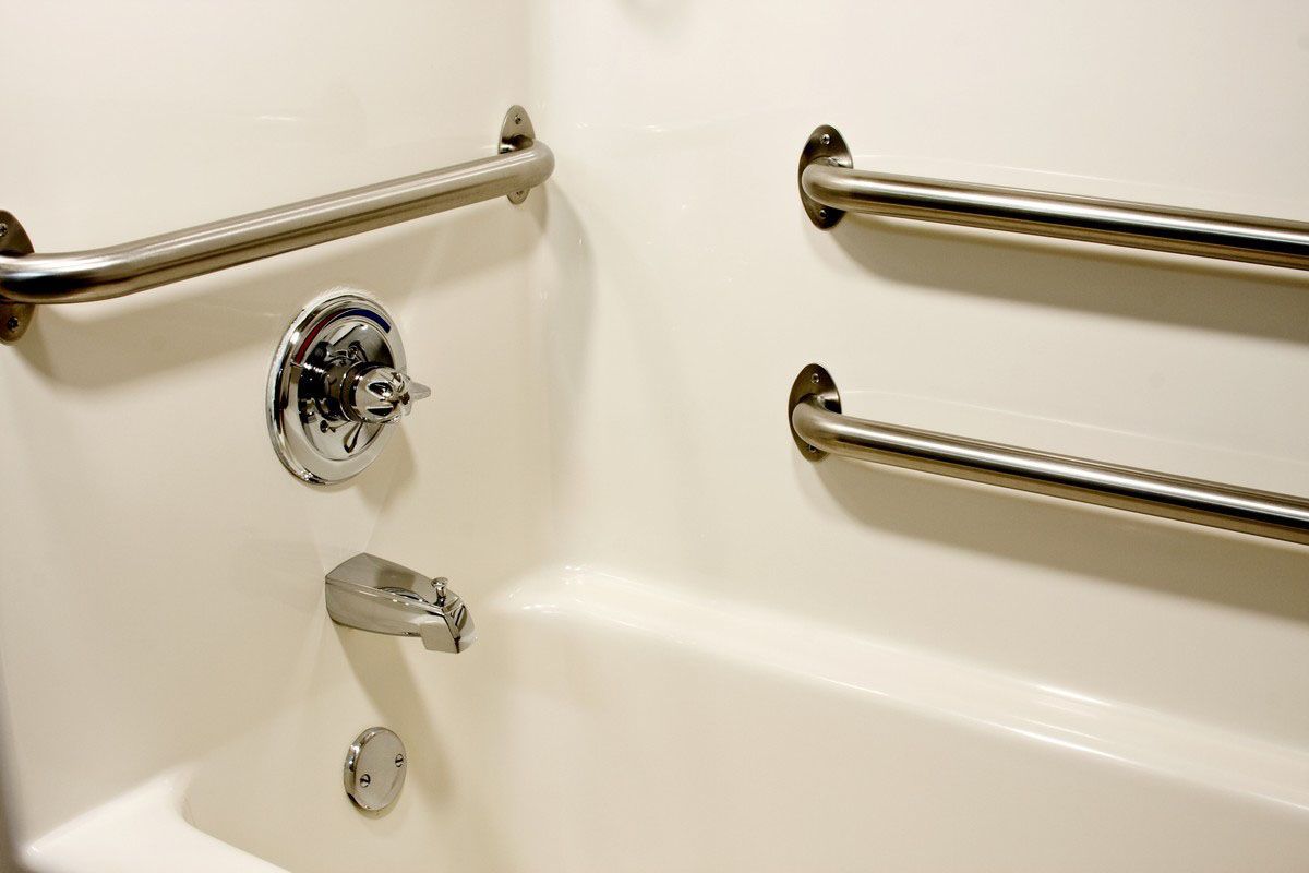 White bathtub with chrome fixtures and grab bars for accessibility.