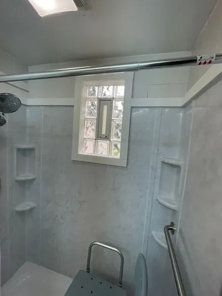 Shower stall with built-in bench, grab bar, and glass block window.