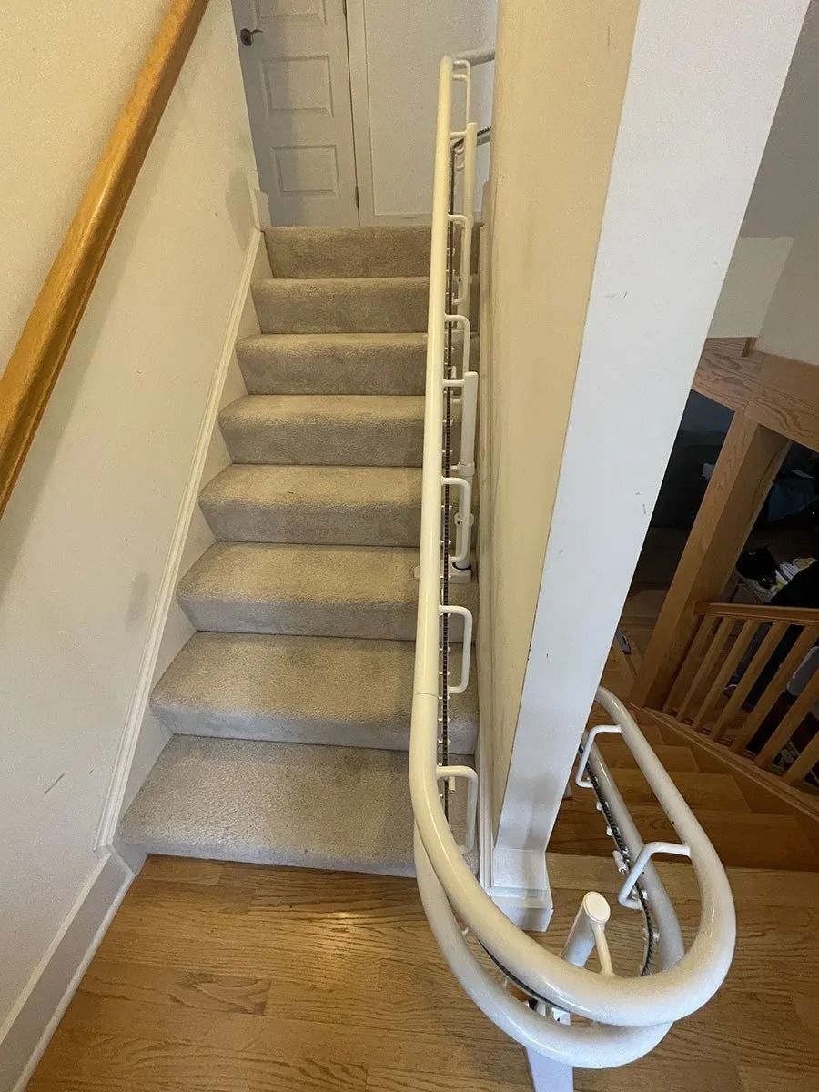 Staircase with carpeted steps and a white handrail. Beige walls and wooden trim.
