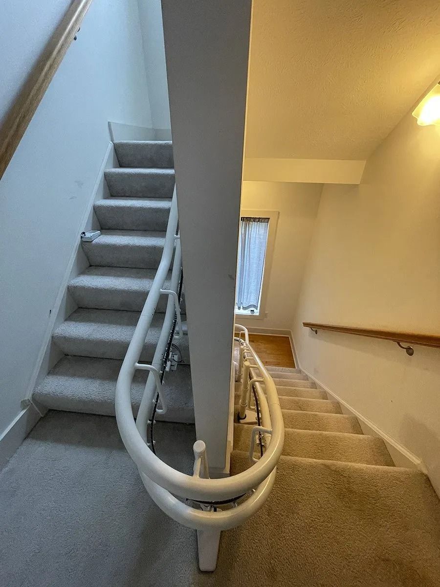 Staircase with carpeted steps and white railing. Handrail on wall and center post.