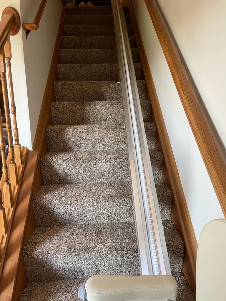 Staircase with carpet and a stair lift installed in a residential setting.