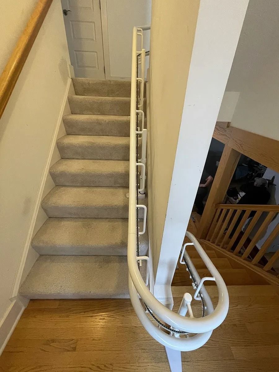 Staircase with carpeted steps and white handrails. Wooden floor and walls.