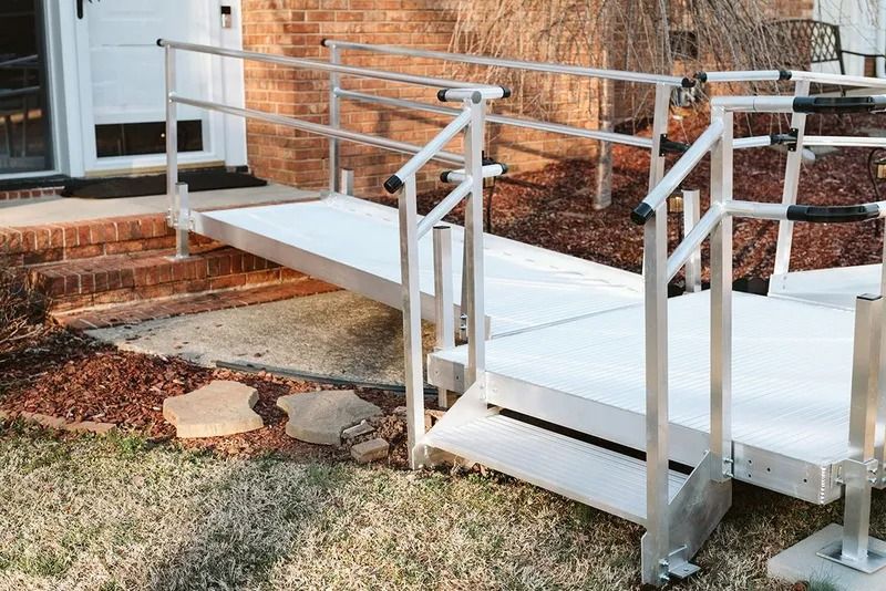 Aluminum ramp with handrails providing accessible entry to a brick house.