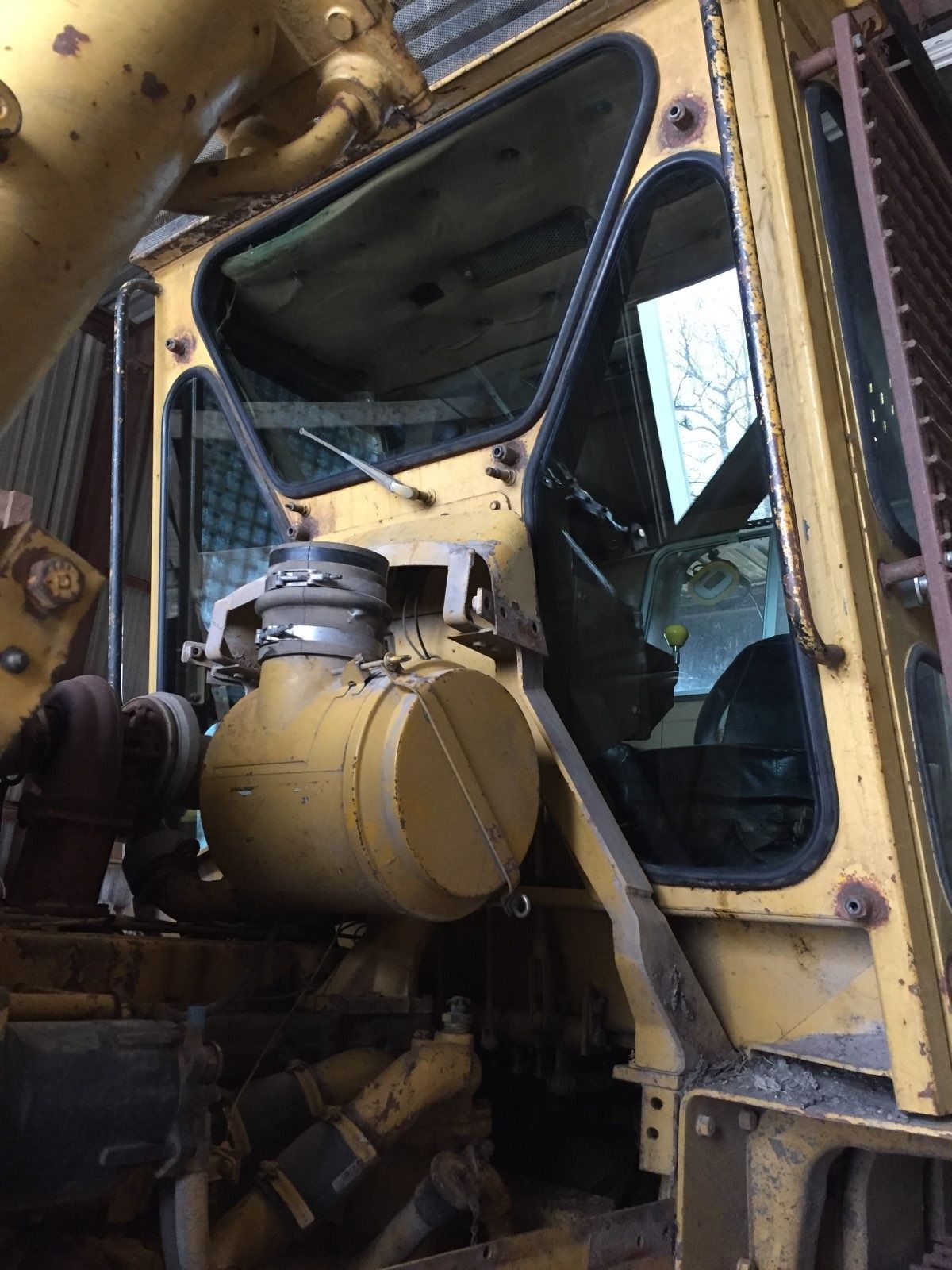 Yellow heavy machinery cab with open door and engine components.