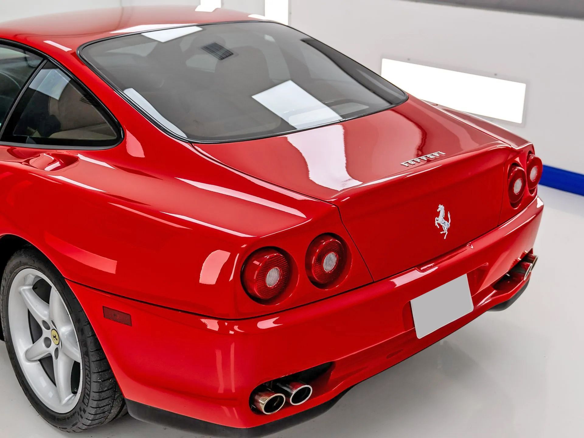 Red Ferrari sports car, rear view, in a showroom.
